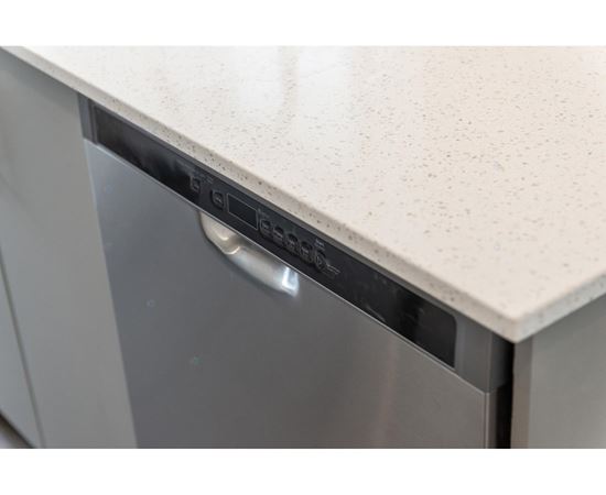 A dishwasher with a silver handle is on a counter.