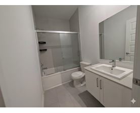 A white bathroom with a toilet, sink, and shower.