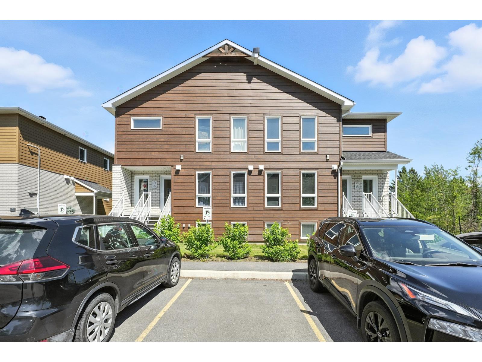 Two black cars are parked in front of a two-story building.