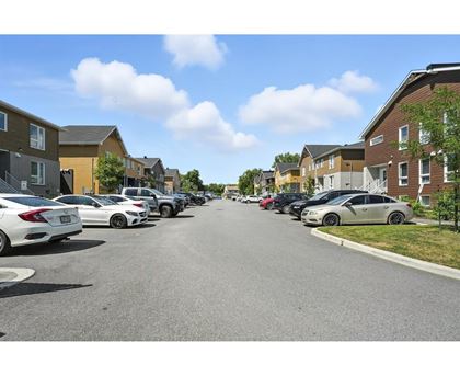 A row of cars parked on a street in front of apartment buildings.