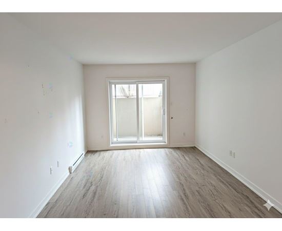 A room with a large window and wooden flooring.