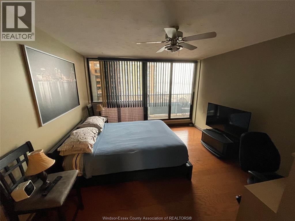 A bedroom with a bed, chair, and television.