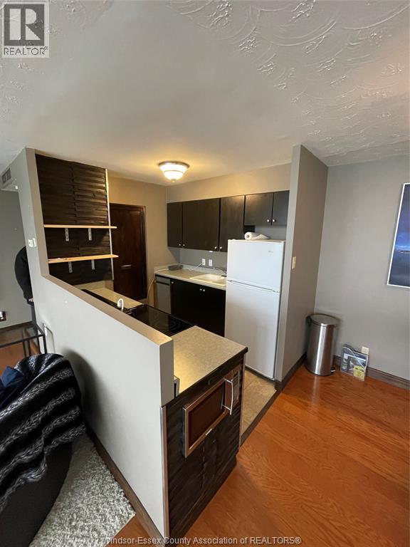 A kitchen with a white refrigerator and wooden floors.