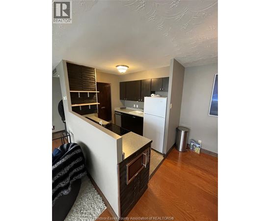 A kitchen with a white refrigerator and wooden floors.