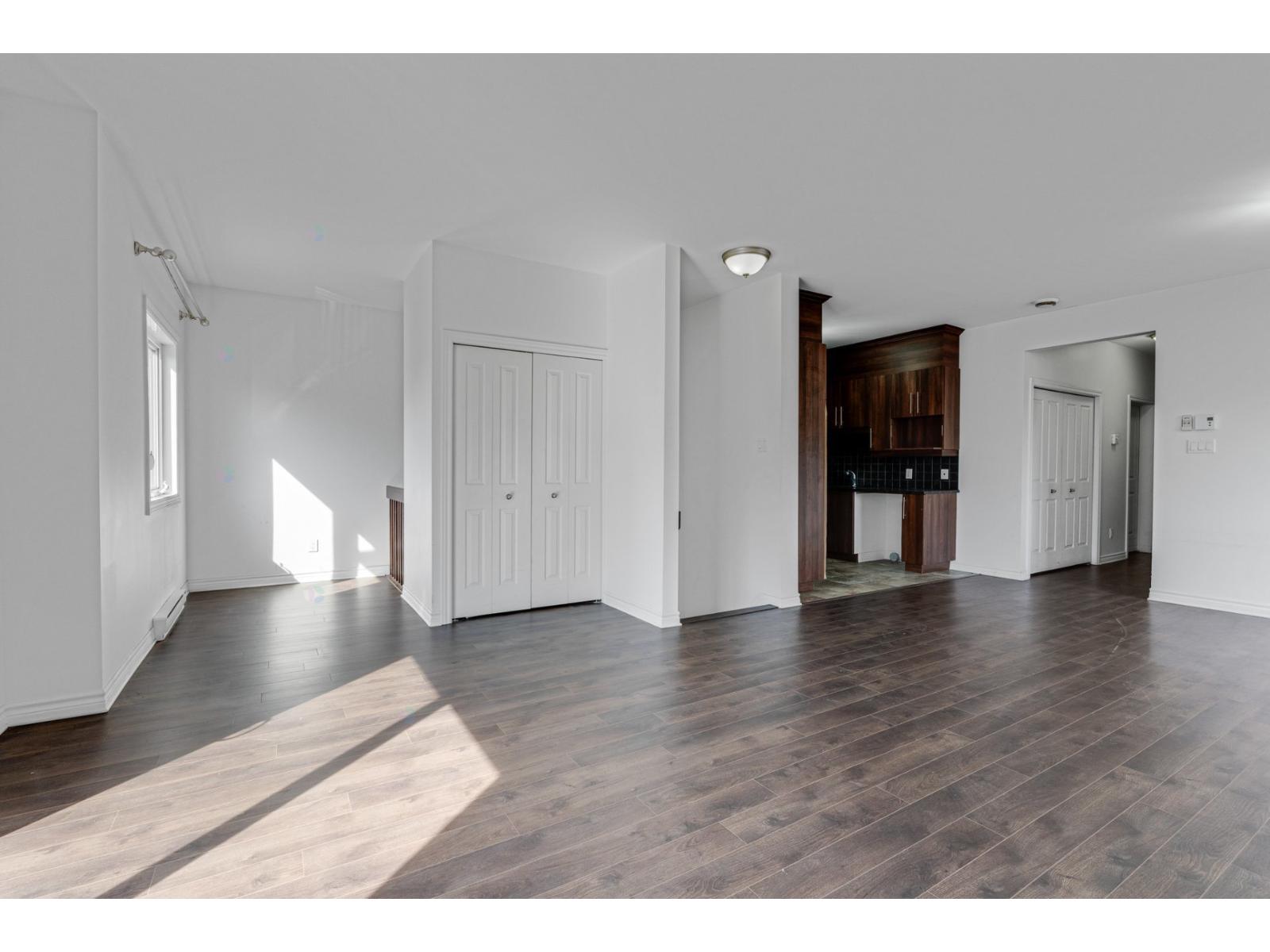A spacious room with wooden flooring and white walls.