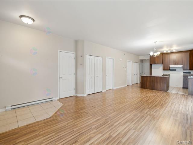 A spacious room with wooden flooring and white walls.