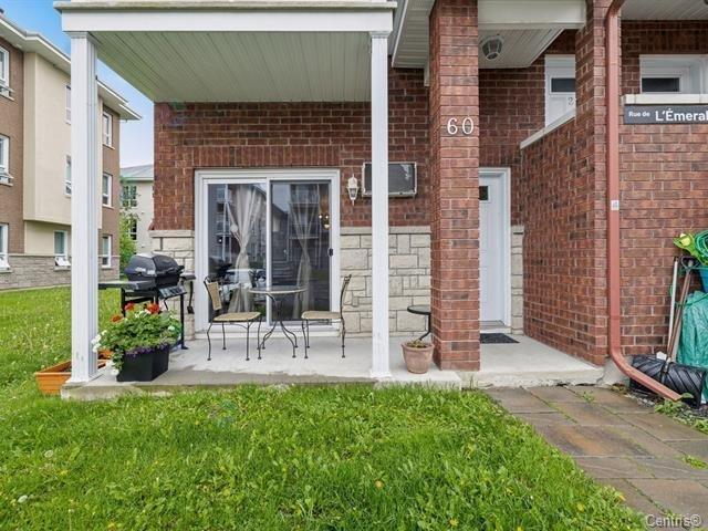 A small patio with a table and chairs is in front of a brick building.