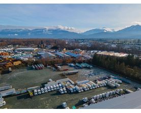 A large parking lot filled with lots of trucks and a mountain range in the background.