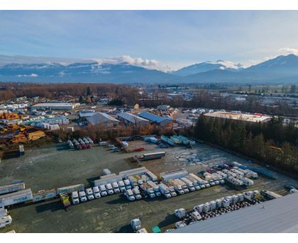A large parking lot filled with lots of trucks and a mountain range in the background.