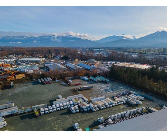 A large parking lot filled with lots of trucks and a mountain range in the background.