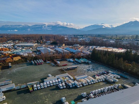 A large parking lot filled with lots of trucks and a mountain range in the background.