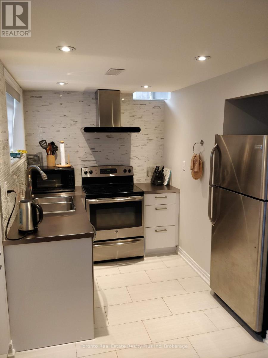 A modern kitchen with stainless steel appliances and a white brick backsplash.