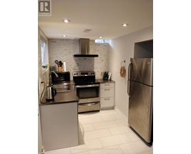 A modern kitchen with stainless steel appliances and a white brick backsplash.