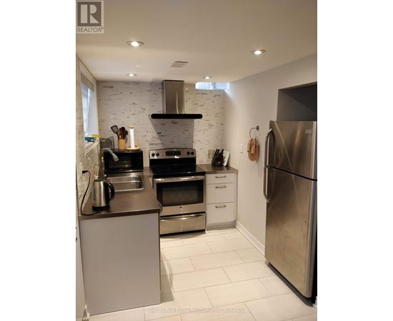 A modern kitchen with stainless steel appliances and a white brick backsplash.