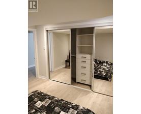 A bedroom with a bed, chair, and wardrobe.