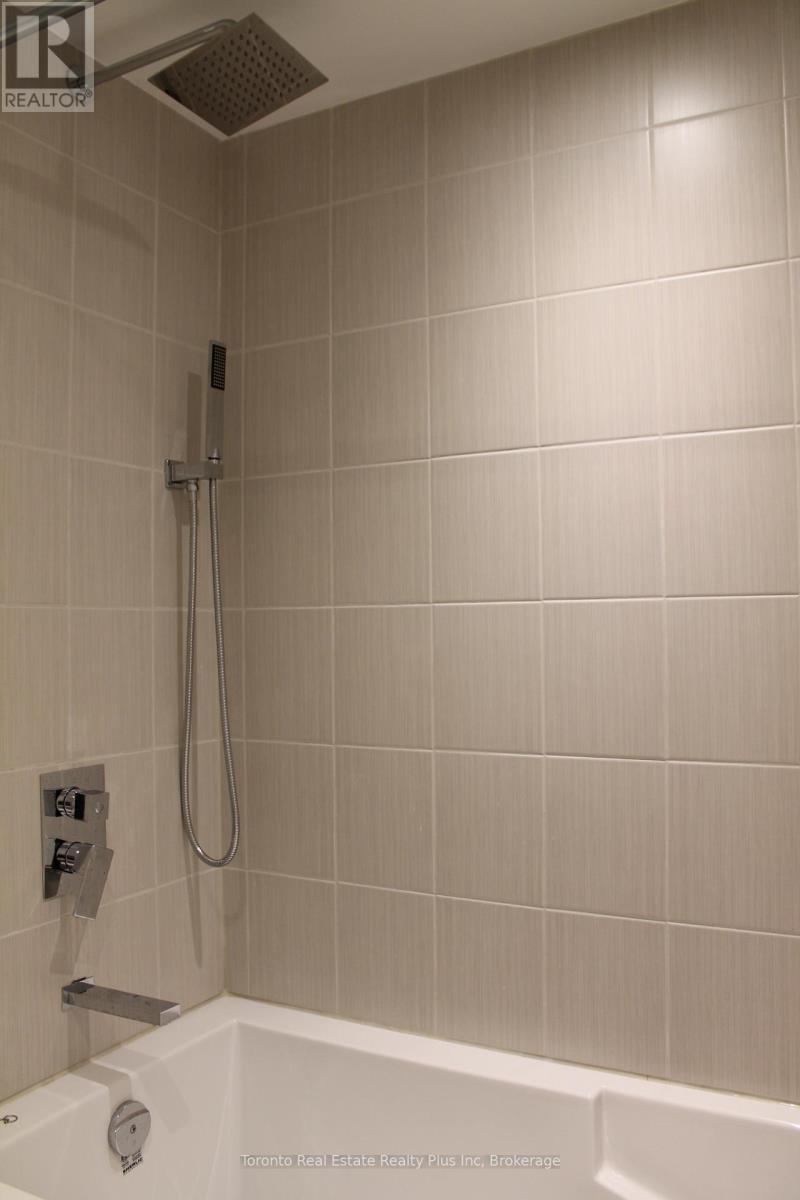 A shower area with a white tub and a silver shower head.