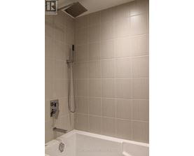 A shower area with a white tub and a silver shower head.