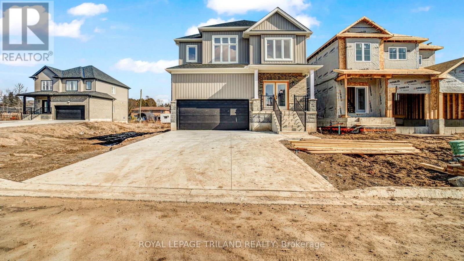 A real estate brokerage logo is displayed on a construction site with partially built houses.