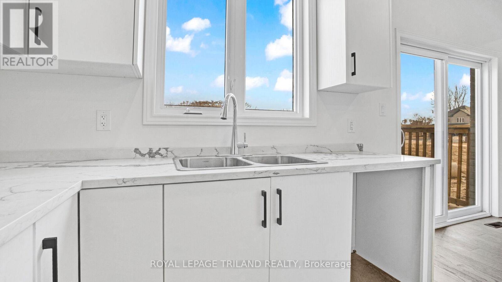 A white kitchen with a sink and a window.