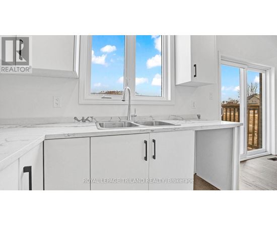 A white kitchen with a sink and a window.