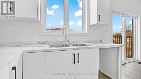 A white kitchen with a sink and a window.