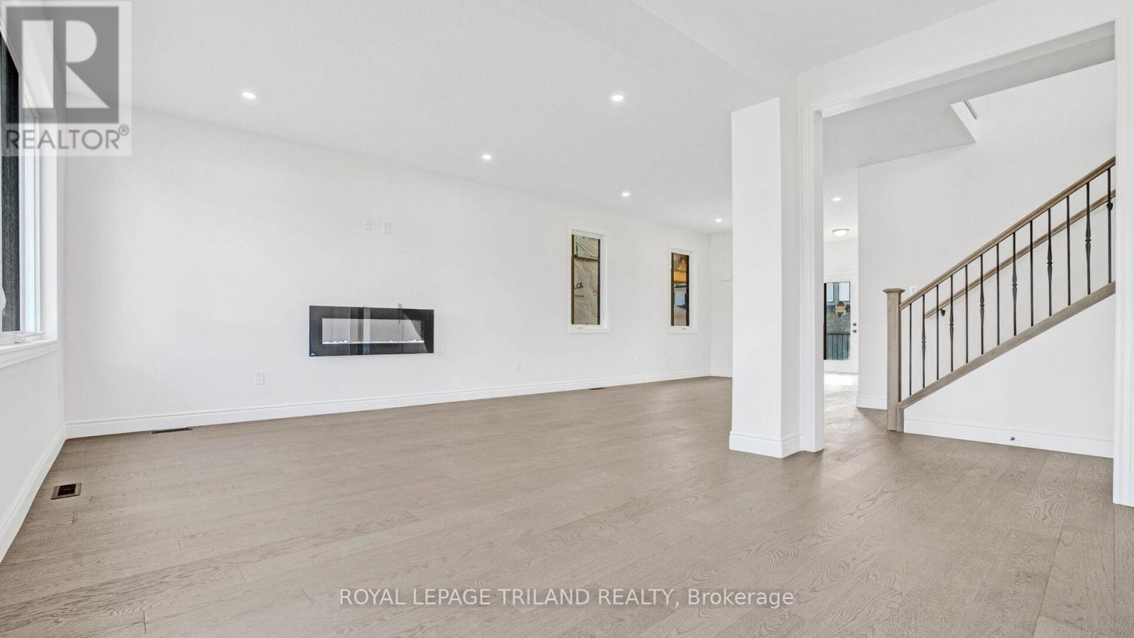 A spacious room with a staircase and a fireplace.