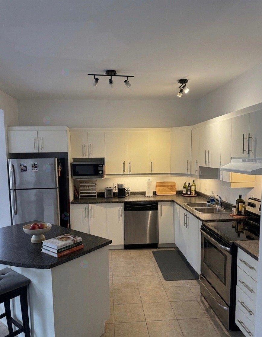 A kitchen with white cabinets and a black countertop.