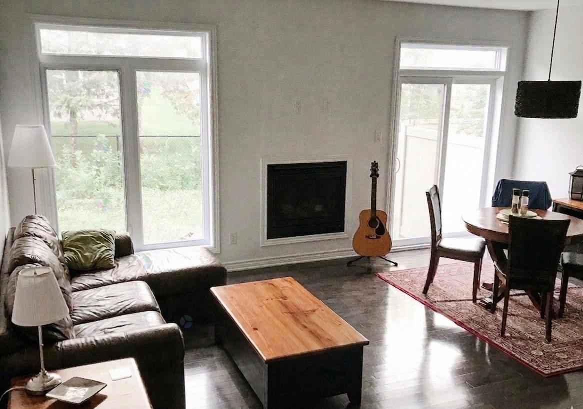 A living room with a fireplace and a guitar leaning against it.