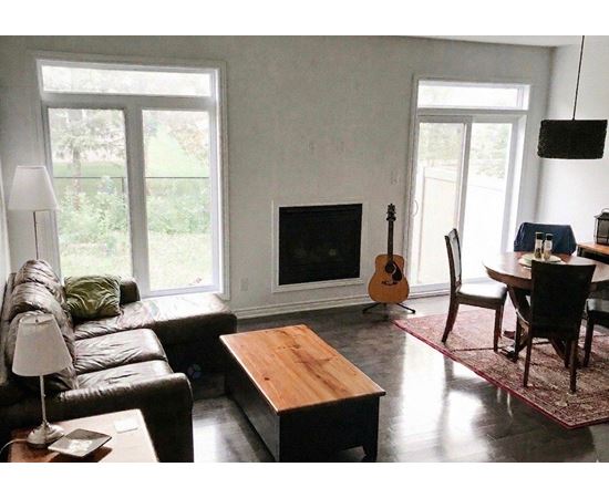 A living room with a fireplace and a guitar leaning against it.