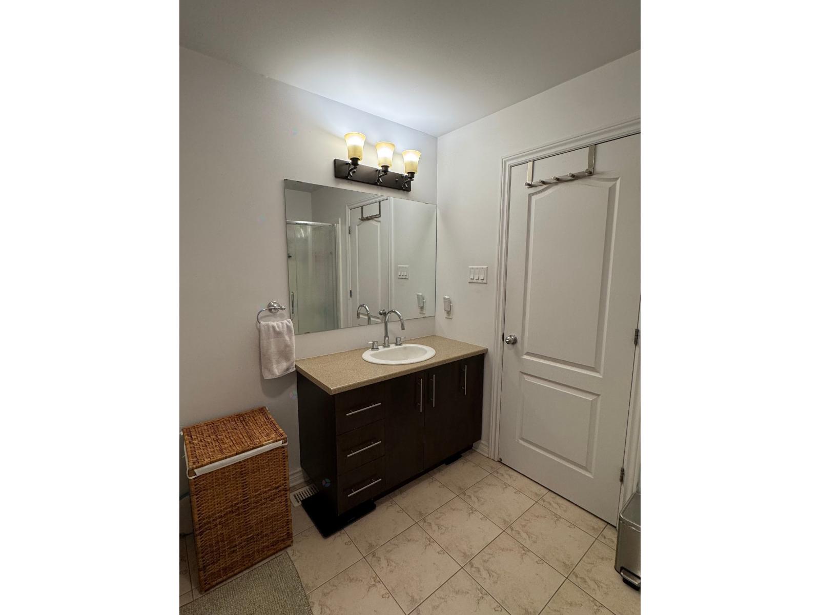 A bathroom with a sink, mirror, and light fixture.