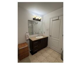 A bathroom with a sink, mirror, and light fixture.
