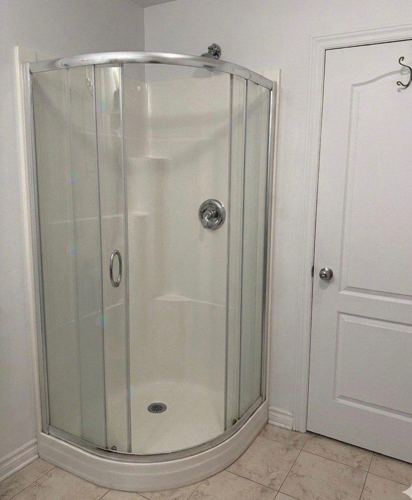 A glass shower stall with a white door.
