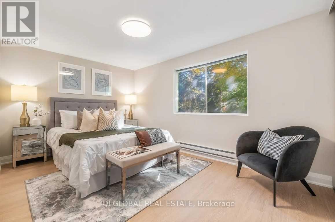 A bedroom with a bed, a chair, and a table with a lamp on it.