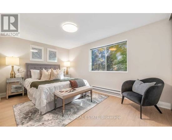 A bedroom with a bed, a chair, and a table with a lamp on it.