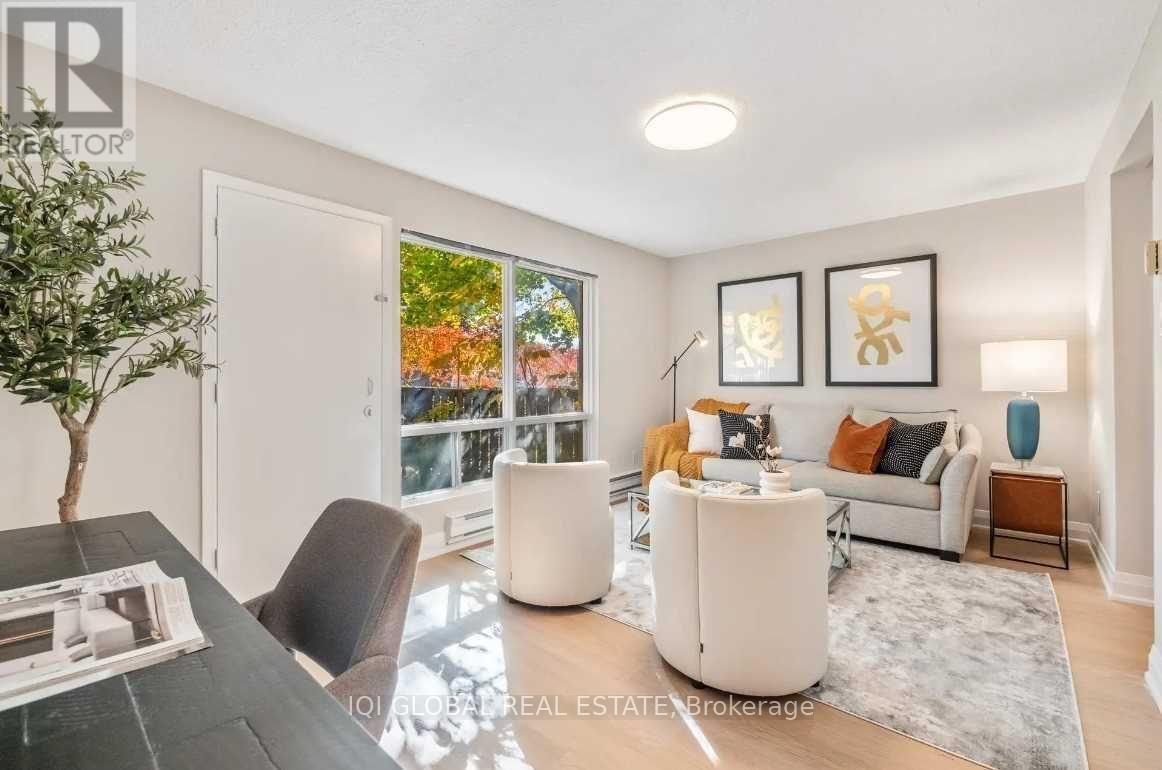 A living room with a white couch, a black chair, and a coffee table with a plant on it.