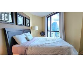 A bedroom with a large bed and a window overlooking a cityscape.