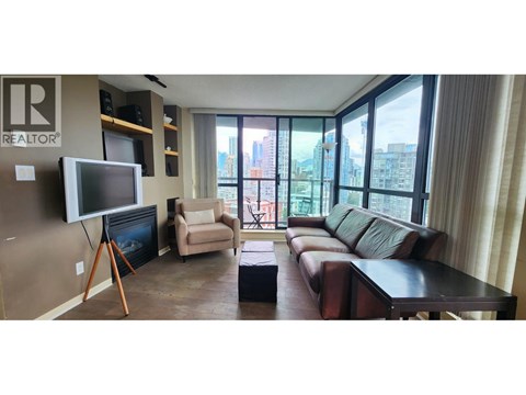 A living room with a brown leather couch and a flat screen TV mounted on the wall.