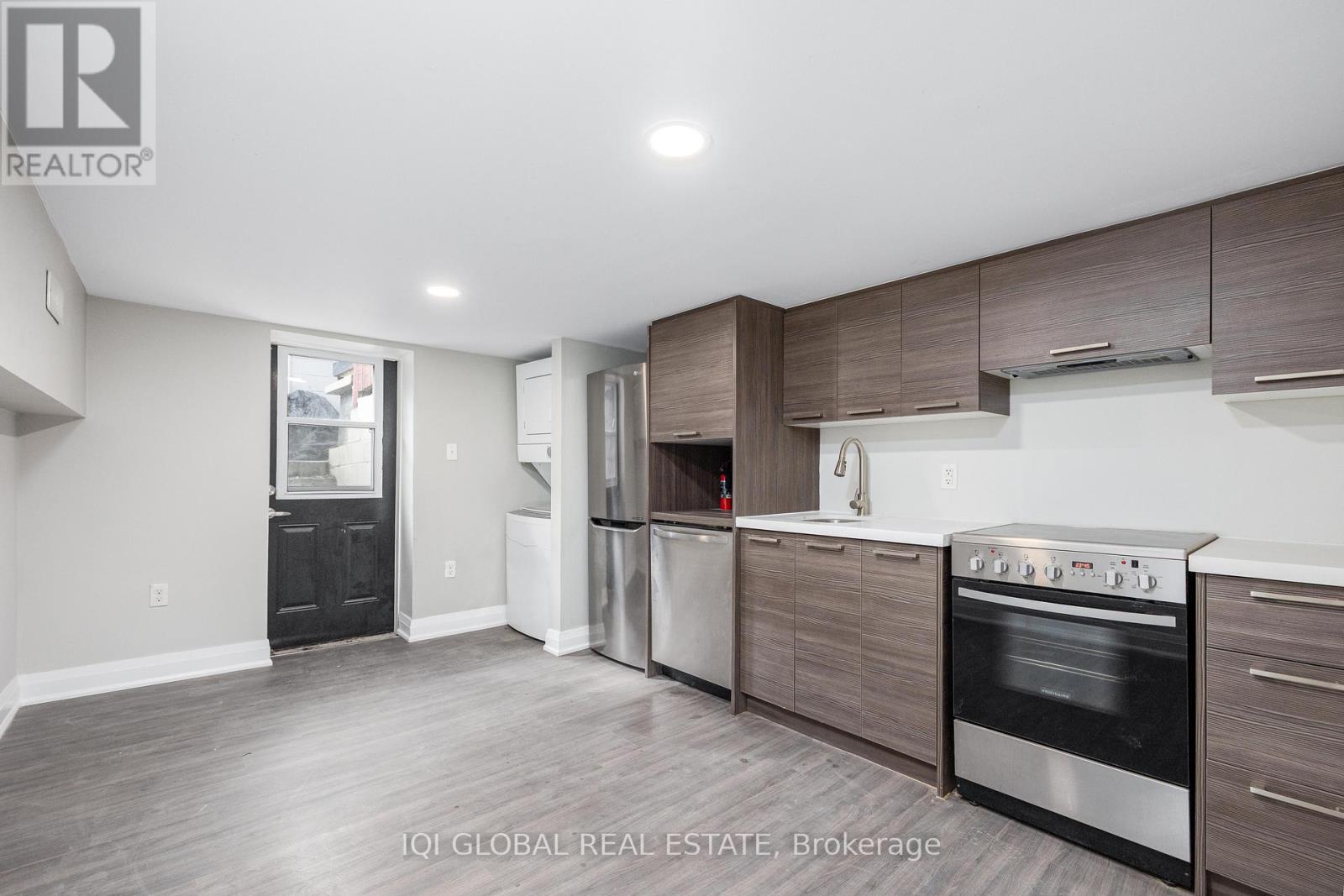 A modern kitchen with dark wood cabinets and stainless steel appliances.