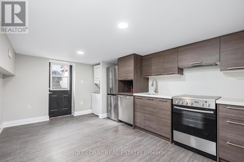 A modern kitchen with dark wood cabinets and stainless steel appliances.