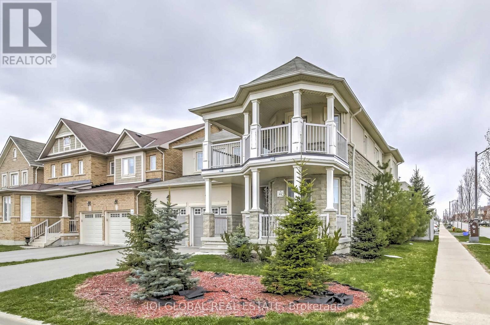 A large house with a balcony is surrounded by smaller houses.