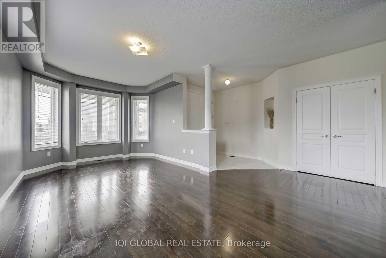 A spacious room with wood flooring and white walls.