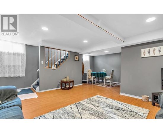 A living room with a staircase and a dining table set up.