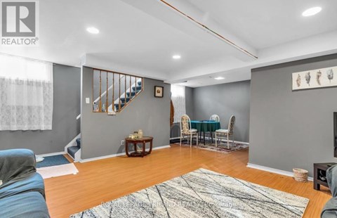 A living room with a staircase and a dining table set up.
