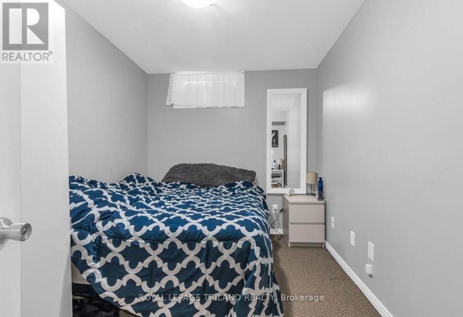 A bedroom with a bed, nightstand, and lamp.