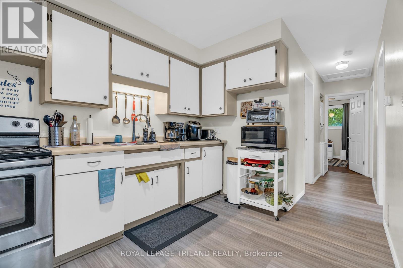A kitchen with white cabinets and a wooden floor.