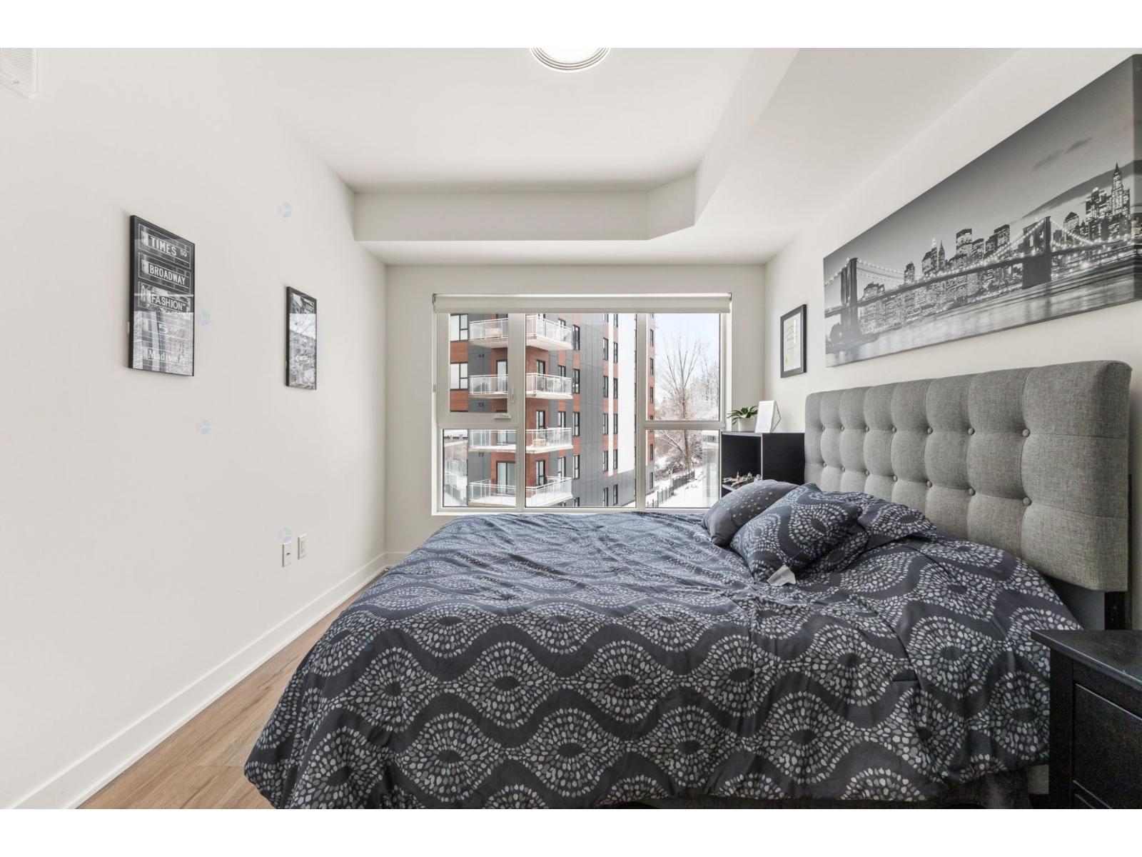 A bedroom with a large bed and a window overlooking a building.