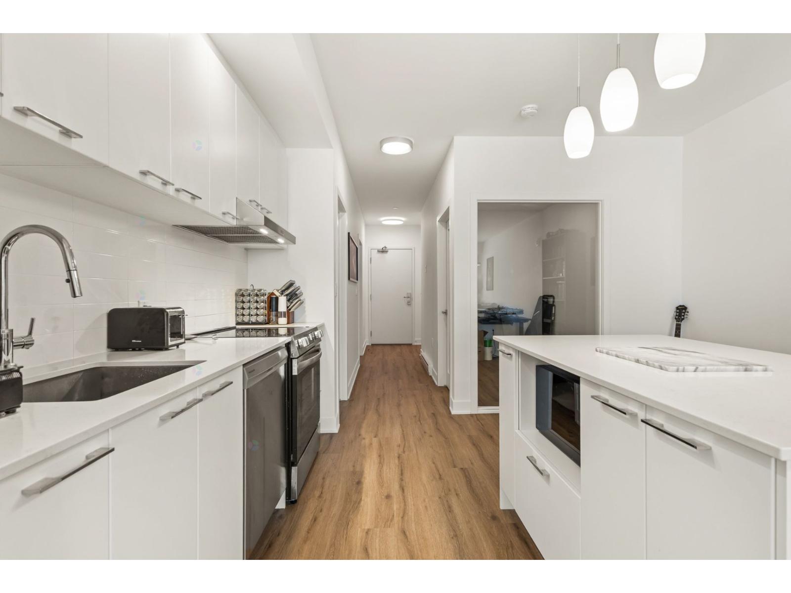 A modern kitchen with white cabinets and a wooden floor.