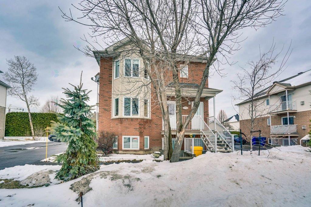 A red brick house with a snow-covered ground and bare trees.