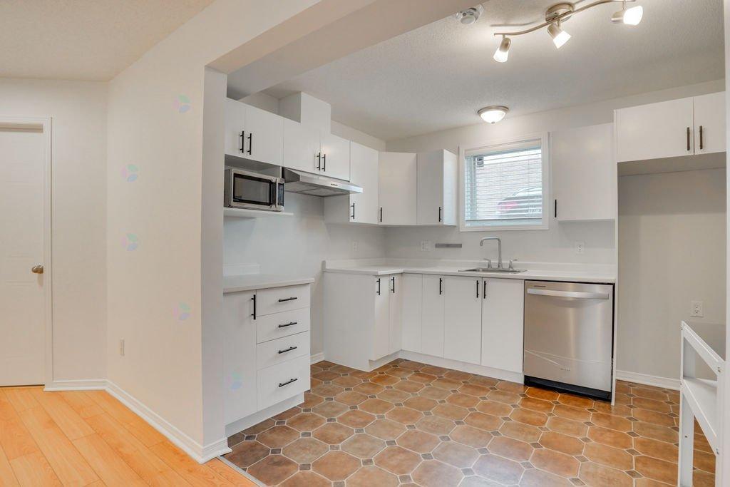 A kitchen with white cabinets and a tile floor.