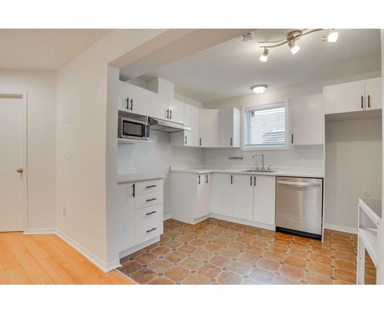 A kitchen with white cabinets and a tile floor.